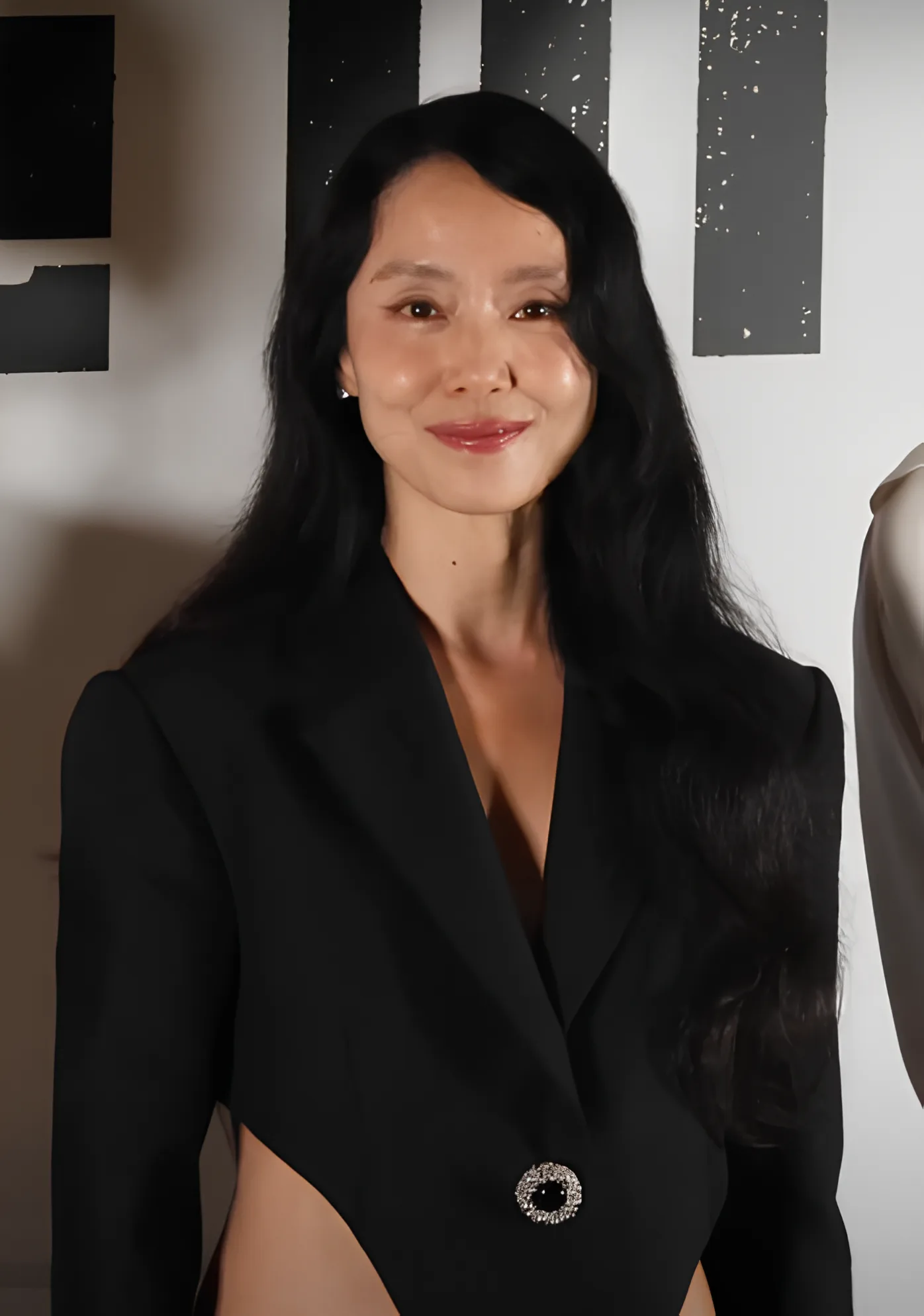 Jeon Do-yeon smiling in a black tailored jacket with long dark hair over one shoulder, at the press preview for the film Revolver, July 2024.
