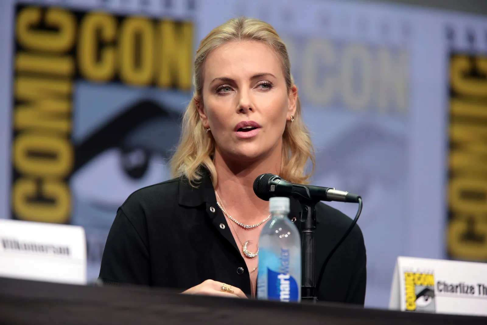 Charlize Theron speaking into a microphone at the 2017 San Diego Comic-Con