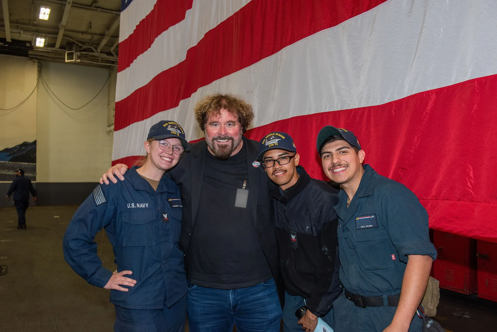 Sean McNamara, director of“Reagan”, poses for a photo with Sailors in the hangar bay onboard Nimitz-class aircraft carrier USS Ronald Reagan (CVN 76), Naval Base Kitsap, in Bremerton, Washington, Aug. 26, 2024. McNamara, and actor Jon Voight participated in a panel discussion on the upcoming featur…