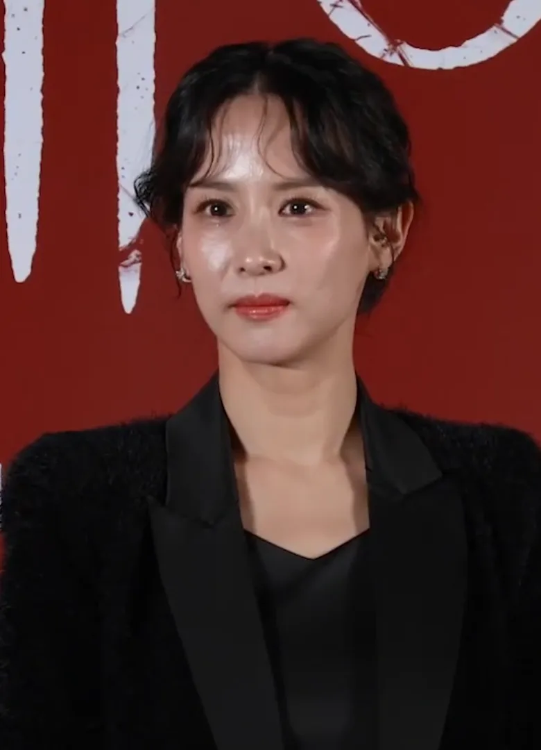 Cho Yeo-jeong with her hair pinned up, in a black textured jacket, against a dark red backdrop at the production briefing for the film Hidden Face, October 2024.