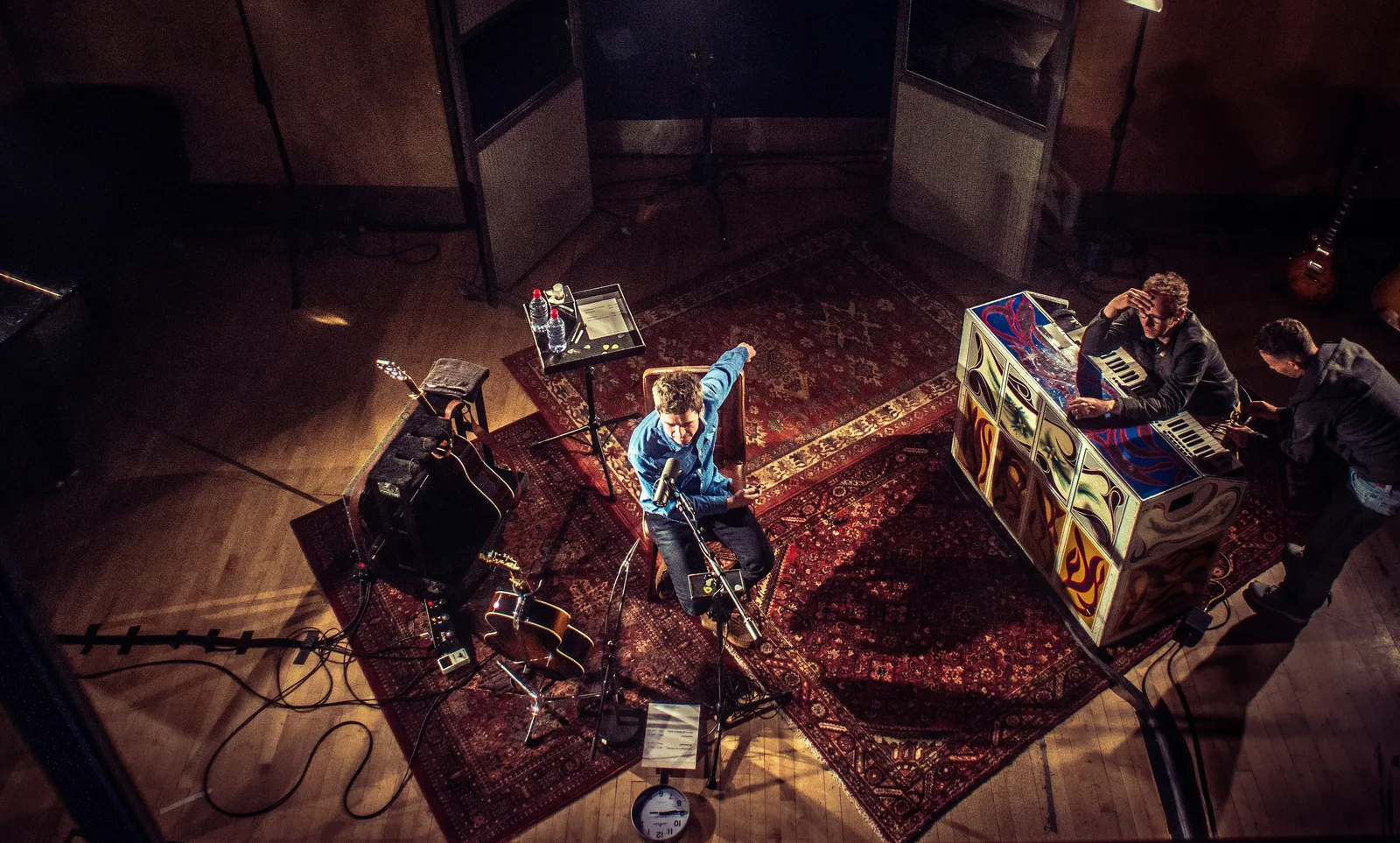 Overhead view of Noel Gallagher (centre, with Gibson J-150) and Mikey Rowe (right, at the psychedelic Oasis keyboard cabinet) performing at Metropolis Studios, London, 2018. The session was filmed for the Apple TV+ documentary Once in a Lifetime Sessions with Noel Gallagher, with performances cut d…