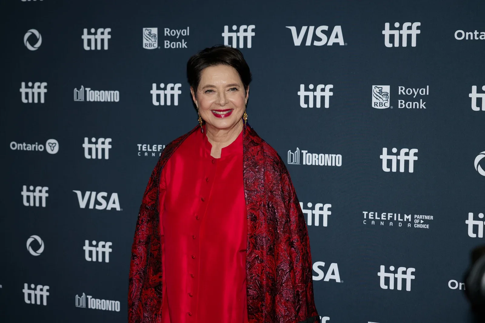 Isabella Rossellini smiling in a red outfit on the 2024 Toronto International Film Festival carpet
